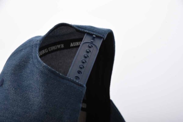 the plastic snap closure on the back of the dark blue washed baseball cap SFA-210329-1